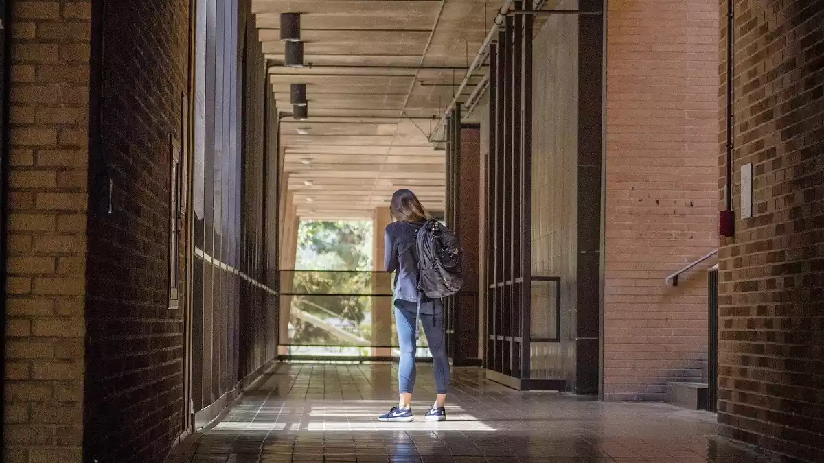 Una alumna caminant pel passadís d'un centre escolar