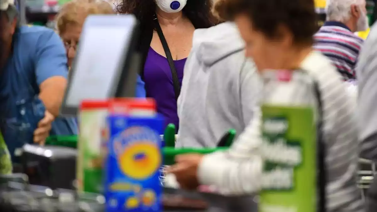 Una dona amb una mascareta comprant en un supermercat
