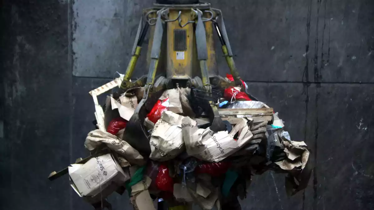Pla tancat del ganxo d'una grua elevant diverses bosses de residus sanitaris per introduir-les al forn de la incineradora de Tarragona