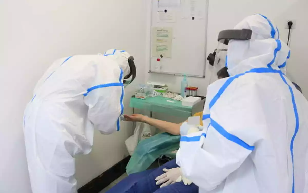 Professionals del CAP Manso, amb equip de protecció individual (EPI), en el moment d'extreure una mostra de sang amb una punxada al dit a una participant a l'estudi de seroprevalença del coronavirus a nivell estatal. 30 d'abril del 2020.