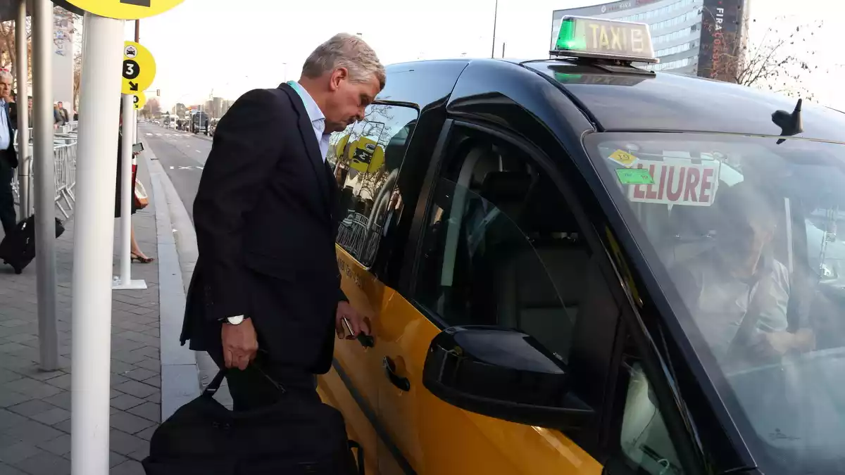 Un congressista puja al taxi a la zona de recollida a la sortida del Mobile World Congress