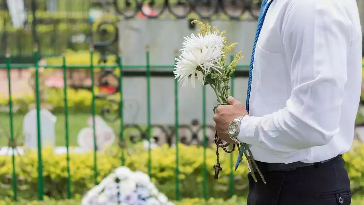 Hombre con flores ante una tumba