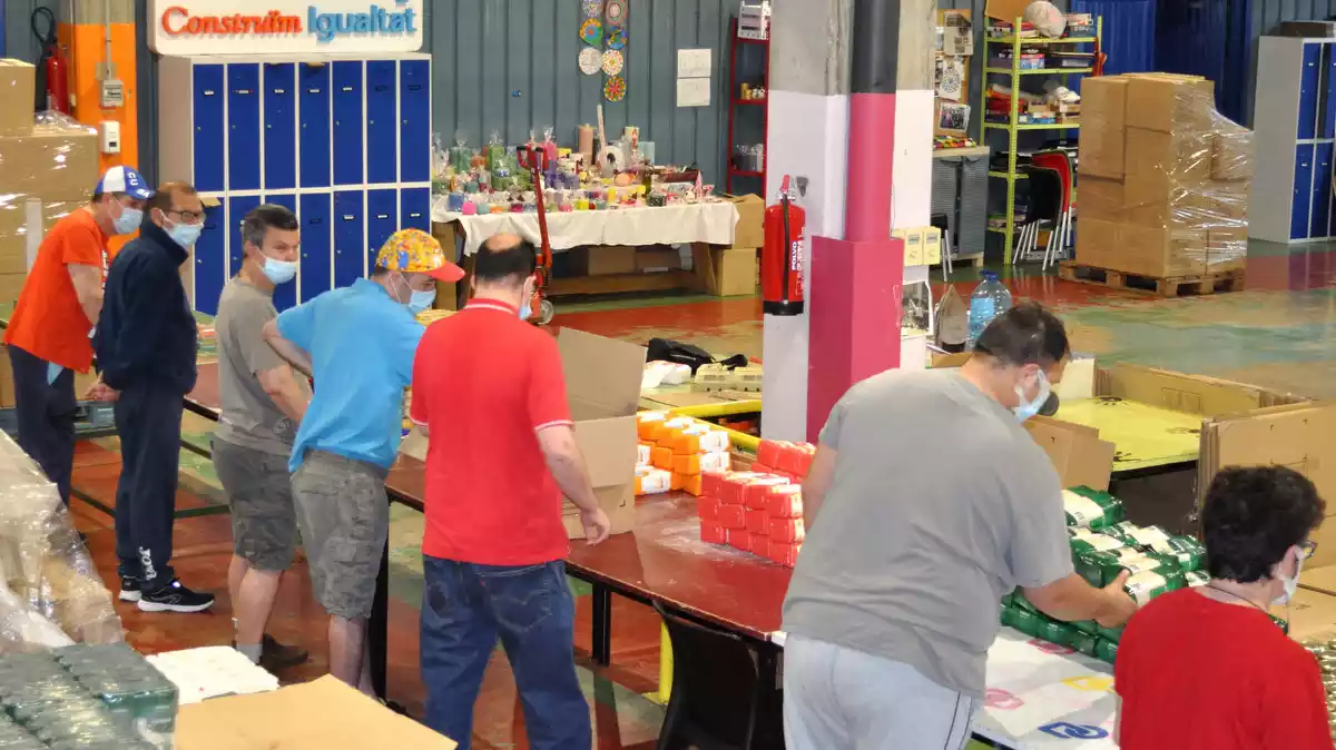 Treballadors del Taller Baix Camp preparant lots d'aliments bàsics