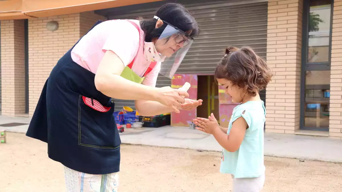 Pla general de la directora de la llar d'infants municipal del Catllar, amb una nena, rentant-se les mans.