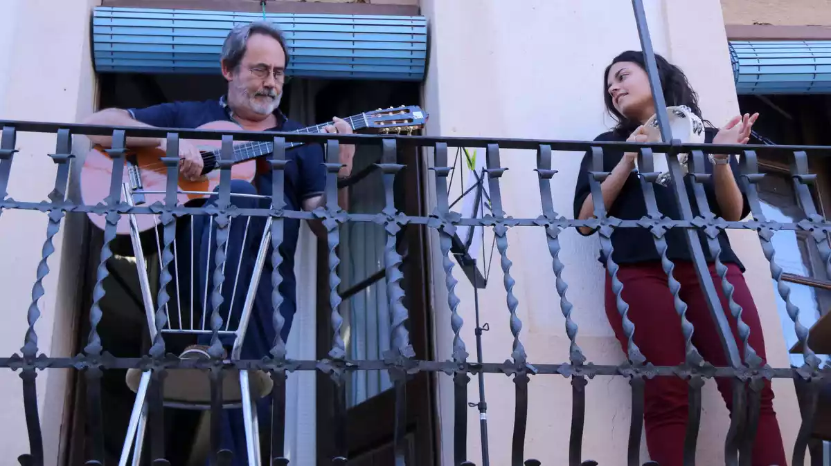 Pla conjunt de Lluís Fernández i la seva filla Núria interpretant jotes i cançons des del balcó de casa per als veïns de Freginals