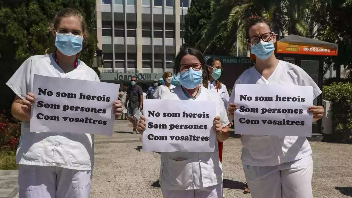 Tres sanitàries porten pancartes en la protesta davant Joan XXIII
