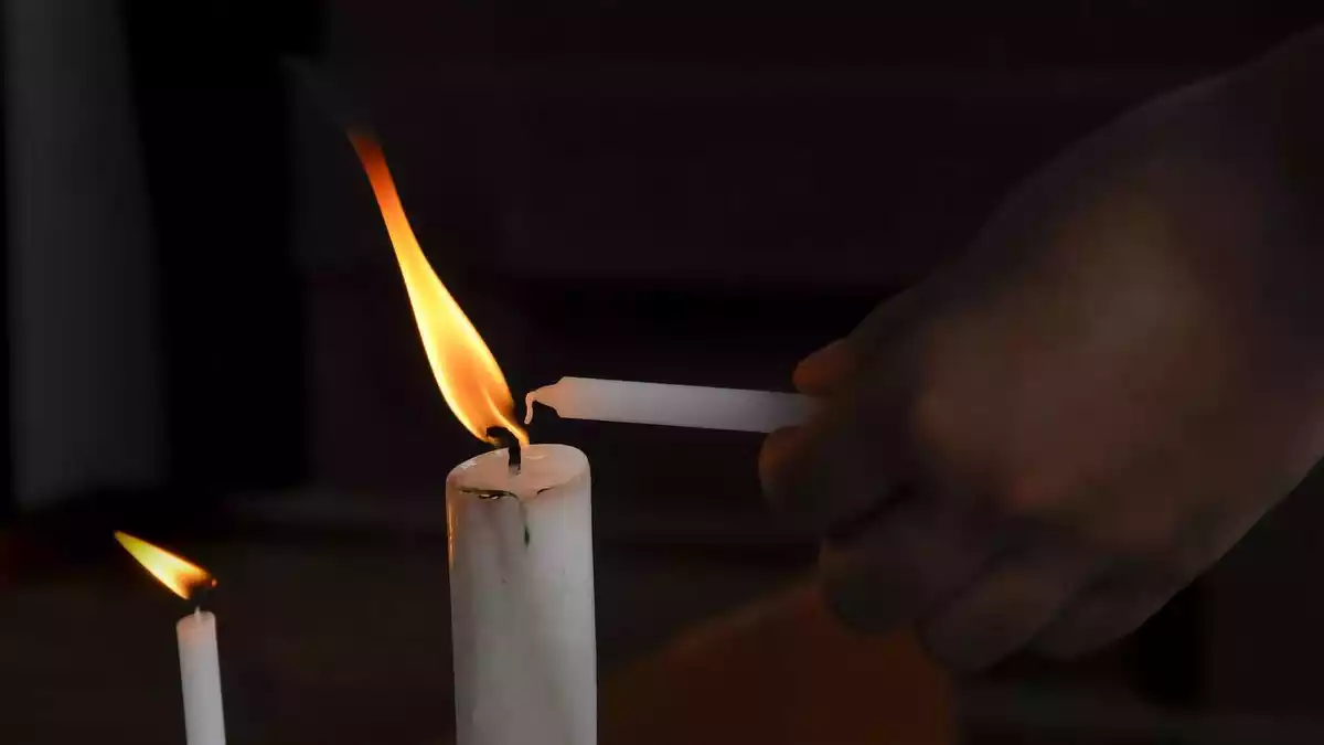 Una persona encenent una espelma